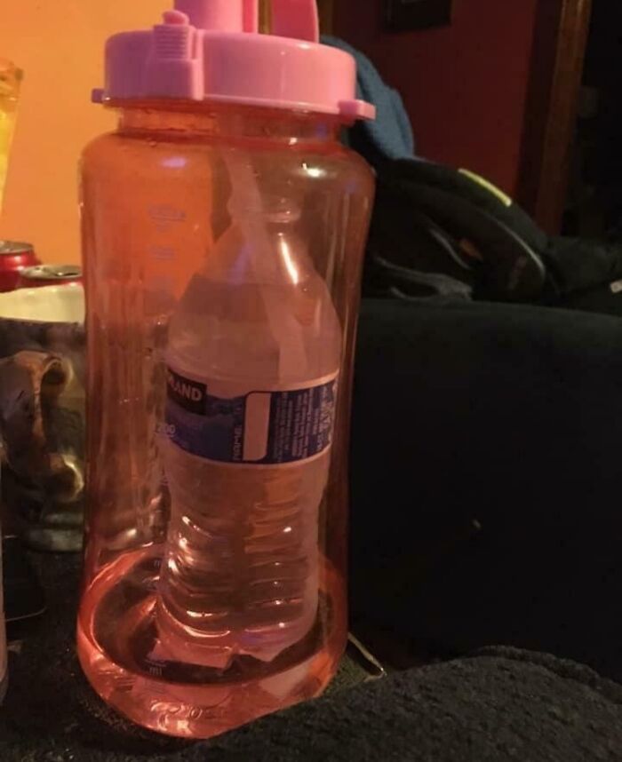 Botella de agua pequeña dentro de una botella grande con tapa rosa; humor de novios divertidos.