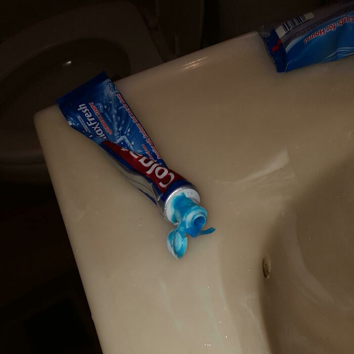 Tubos de pasta dental abiertos y mal colocados en lavabo, mostrando ignorancia de normas básicas de educación y respeto en el baño.