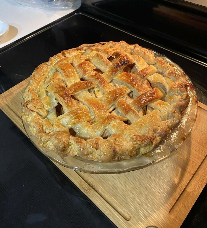 Tarta casera con repostería de masa entrelazada crujiente dorada recién horneada sobre tabla de madera.