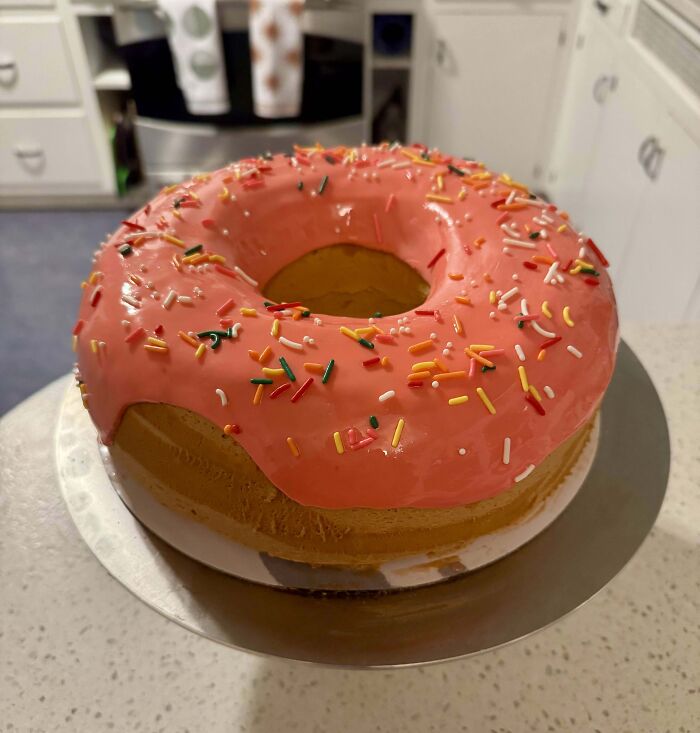 Rosca de repostería con glaseado rosa y chispas de colores, mostrando creatividad y técnica avanzada en repostería.