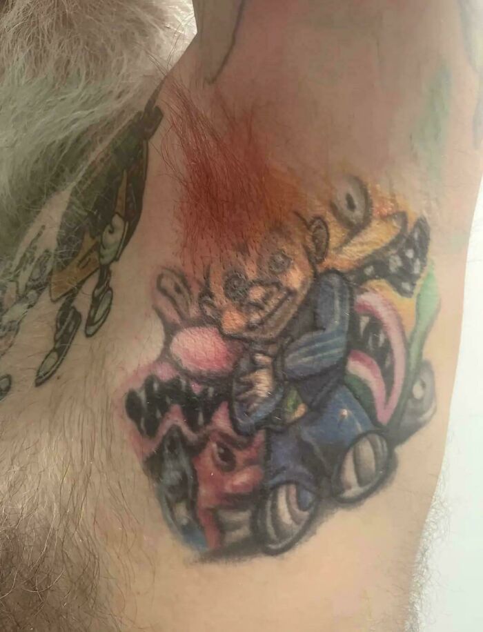 Tatuaje en brazo con diseño de caricatura borroso y colores desgastados, ejemplo de tatuajes mala elección.