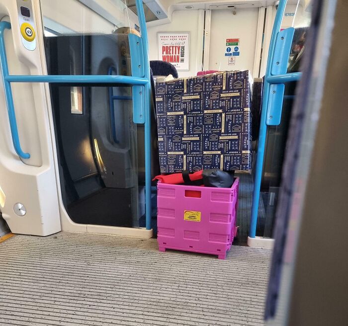Caja rosa obstruyendo el pasillo de un tren, ejemplo de ignorancia y falta de normas básicas de educación pública.