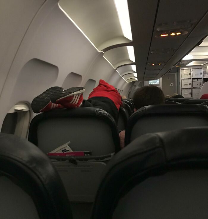 Pasajero acostado con los pies sobre asiento en avión, ignorando normas básicas de educación y respeto.