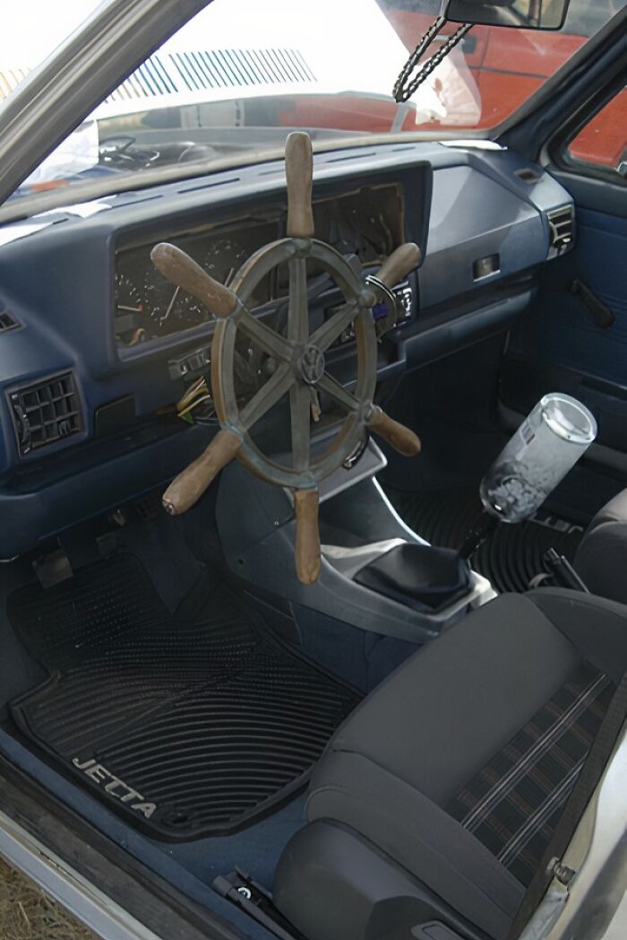 Volante de barco improvisado en el tablero de un coche, reflejando una reparación fallida.