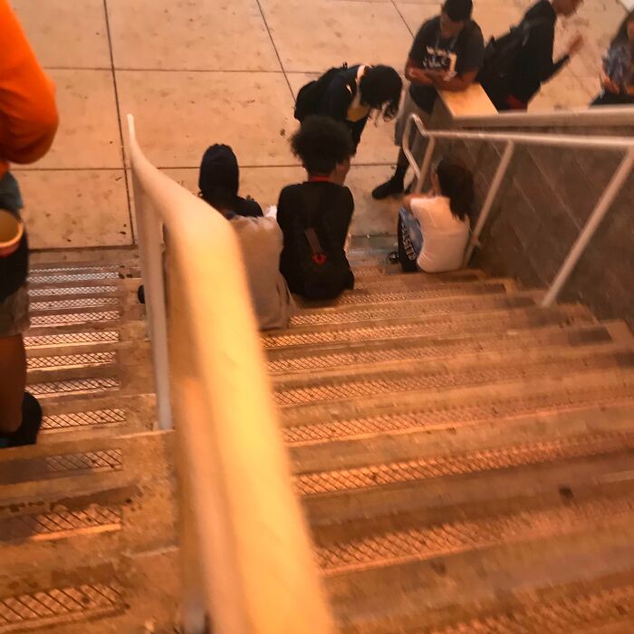 Personas ignorantes sentadas en escaleras públicas sin respetar normas básicas de educación ni espacio personal.