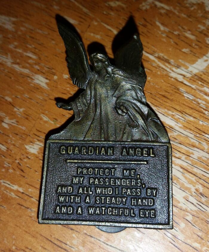 Figura de ángel de la guarda en metal sobre superficie de madera, simbolizando protección para personas con un día peor.