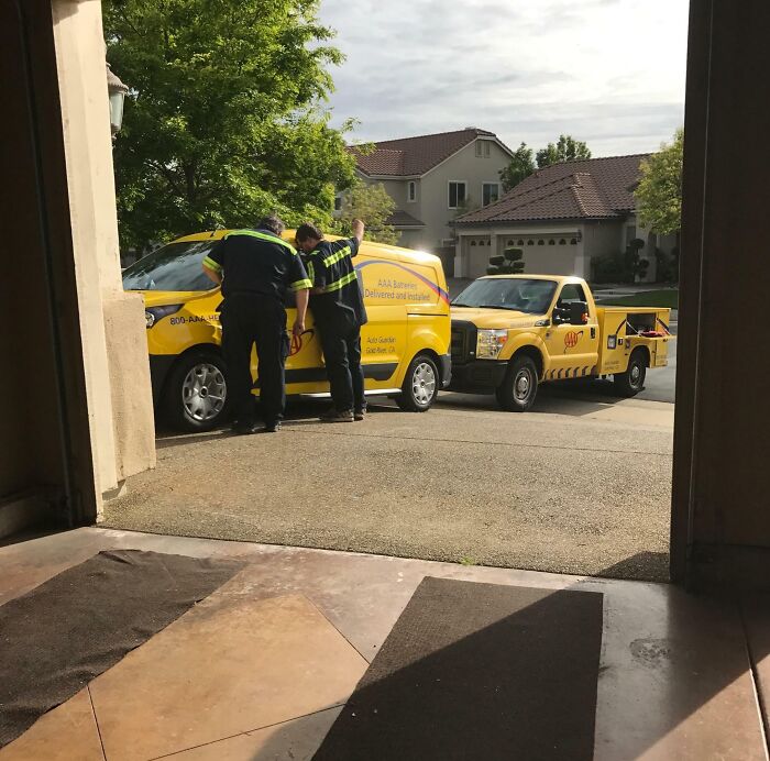 Dos técnicos en vehículos de asistencia AAA reparando una avería, mostrando a personas con un día peor que el tuyo.