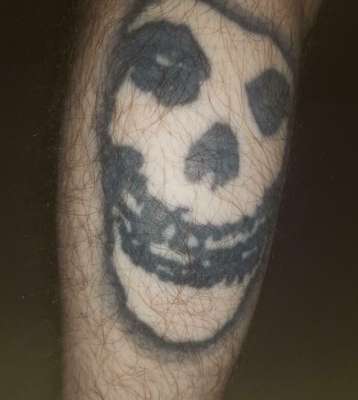 Tatuaje mal diseñado de calavera en pierna con líneas borrosas y aspecto descuidado, ejemplo de mala elección en tatuajes.