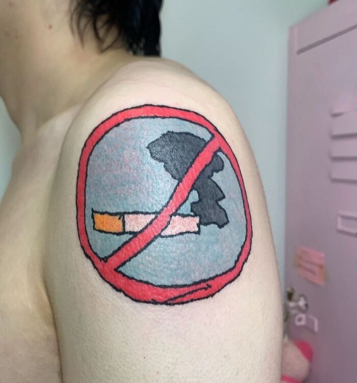 Tatuaje de símbolo de prohibido fumar en el hombro, ejemplo de tatuajes que fueron una mala elección cómica.