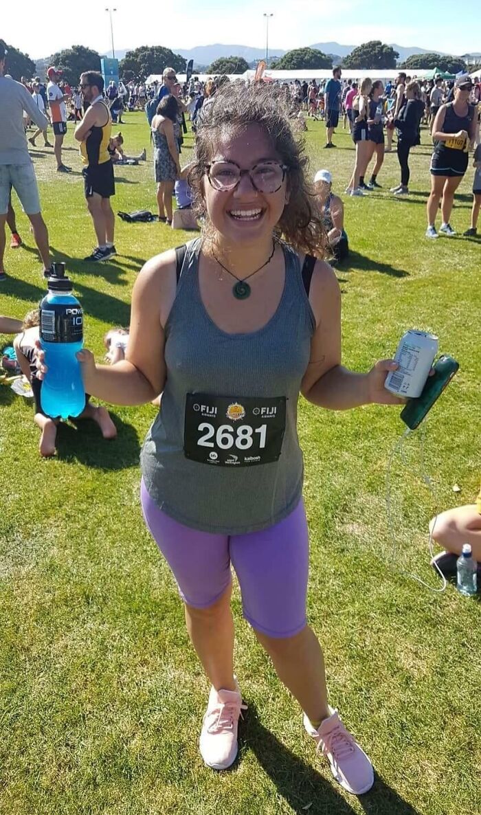 Mujer sonriente con número de corredor en evento deportivo, recobrando la fe en la humanidad con momentos positivos.