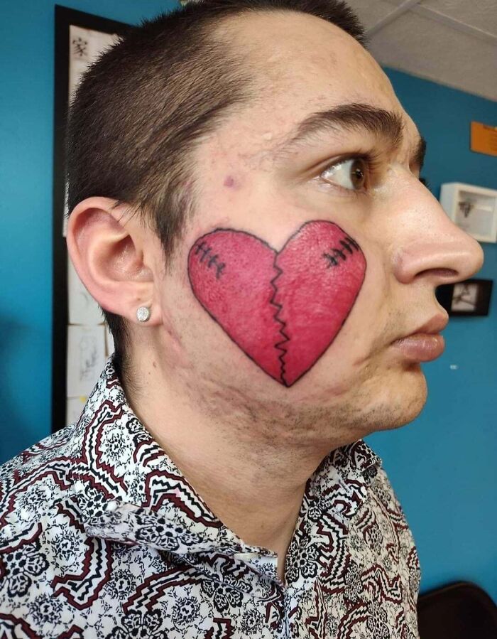 Hombre con tatuaje de corazón roto en la mejilla, ejemplo de tatuajes que fueron una mala elección en la cara.