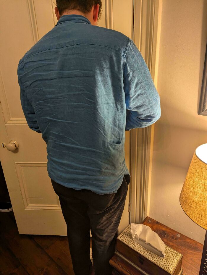 Persona confundida de espaldas en interior con camisa azul y pantalones oscuros, pidiendo ayuda en Internet por duda visual.