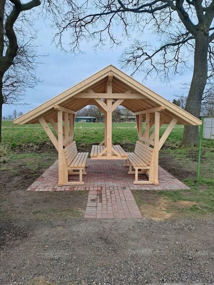 Estructura de madera con banco integrada en zona verde, ejemplo de proyectos que muestran habilidades con la madera.
