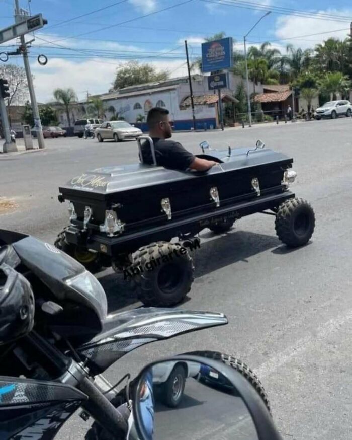 Hombre conduciendo un vehículo modificado con forma de ataúd en una calle vacía, imagen maldita inexplicable.