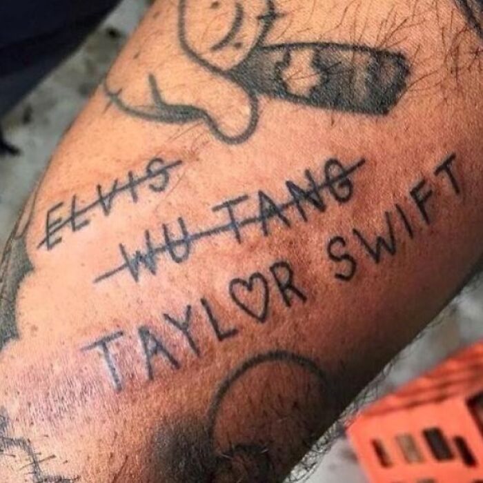 Tatuaje mal hecho con nombres tachados y uno que dice Taylor Swift con un corazón en la piel de un brazo.
