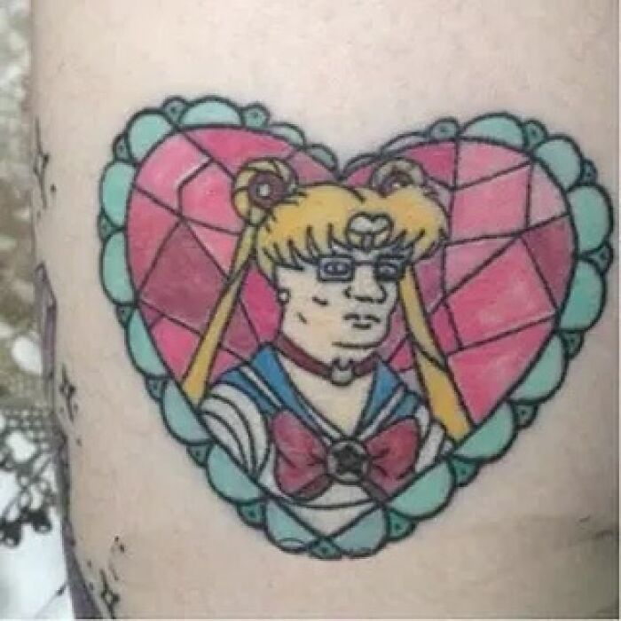 Tatuaje colorido en brazo con diseño de personaje animado dentro de un corazón con estilo poco logrado.