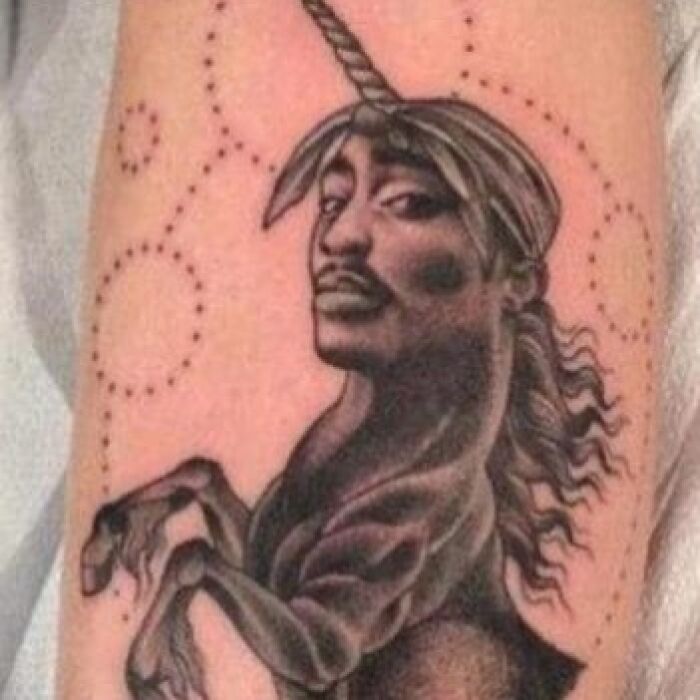 Tatuaje con diseño surrealista de unicornio con rostro humano, ejemplo de tatuajes horribles que no se perciben así.