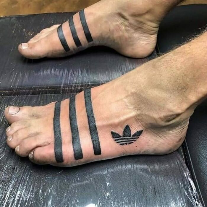 Tatuajes en pies con líneas gruesas y símbolo, ejemplo de personas sin darse cuenta de lo horribles que son sus tatuajes.