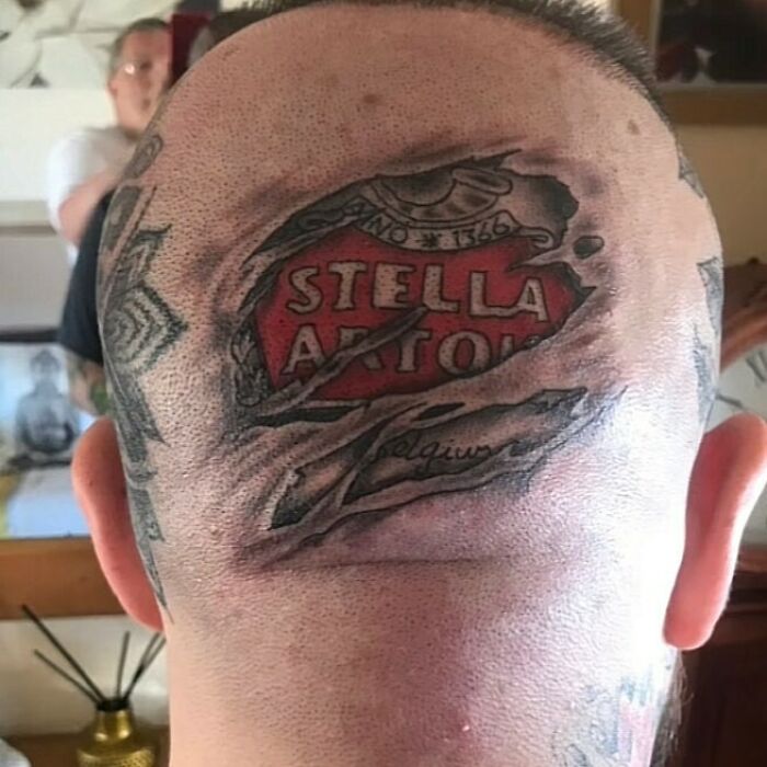 Tatuaje horrible de marca Stella Artois en la parte trasera de la cabeza, parte de tatuajes que no se dan cuenta que son malos.