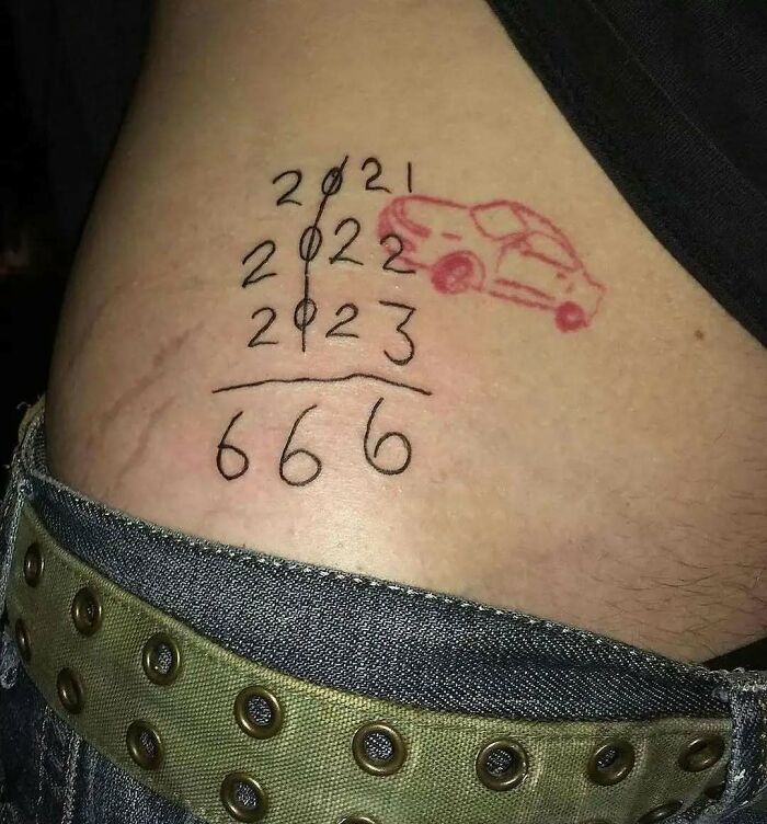 Un tatuaje con números y un dibujo de coche en el abdomen, mostrando un diseño poco convencional.