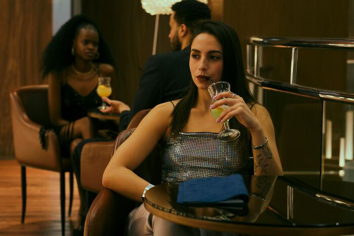 Mujer en bar con expresión pensativa, representando momentos de mujeres que no se van a casar con su pareja.