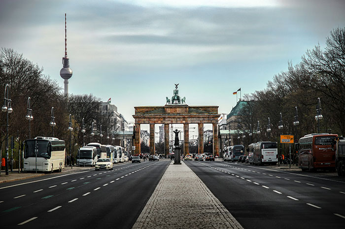 Avenida frente a la Puerta de Brandeburgo en Berlín, destacando el choque cultural arquitectónico.