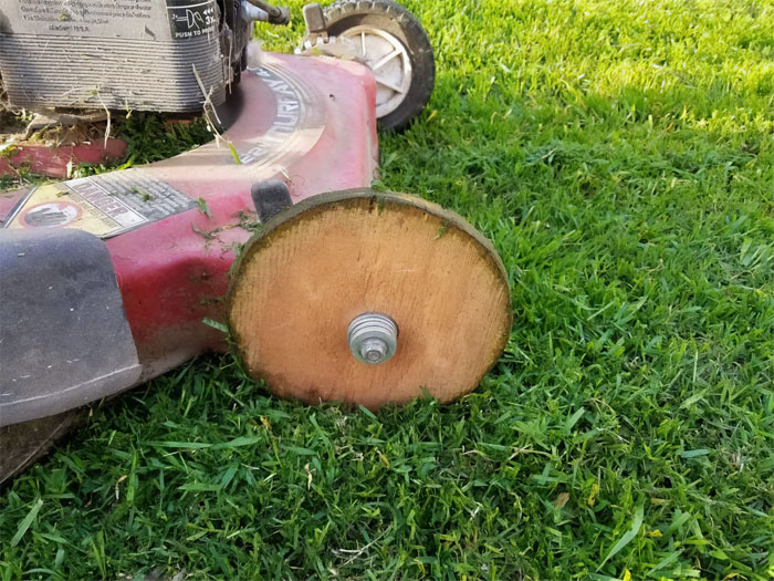 Cortadora de césped con rueda de madera improvisada, mostrando un intento de reparación fallida.