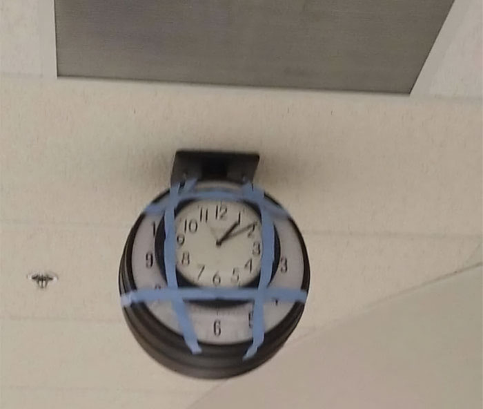 Reloj de pared reparado con cinta, muestra intento fallido de reparación.