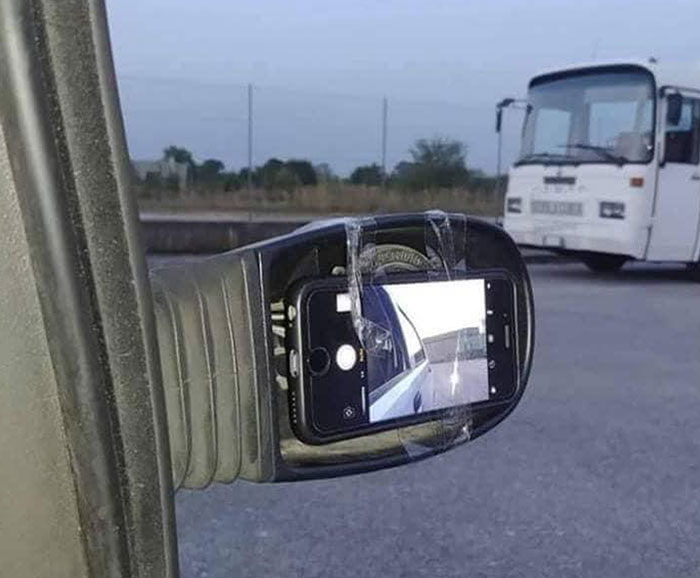 Espejo roto de coche reparado con un teléfono móvil pegado con cinta.
