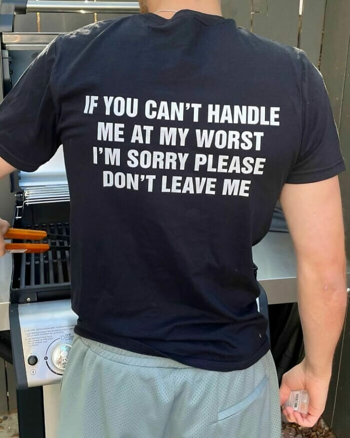 Hombre de espaldas con camiseta negra divertida y ridícula con texto en inglés preparando la parrilla en exterior.