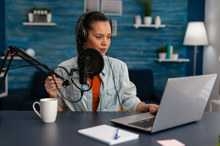 Mujer con auriculares y micrófono, grabando un podcast sobre momentos de mujeres que no se casaron con su pareja.