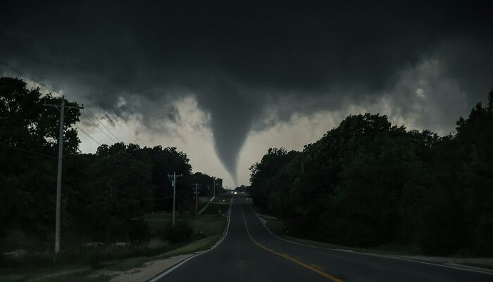 Tornado visible al final de una carretera en un paisaje oscuro, representando momentos para saber que hay que irse ya mismo.