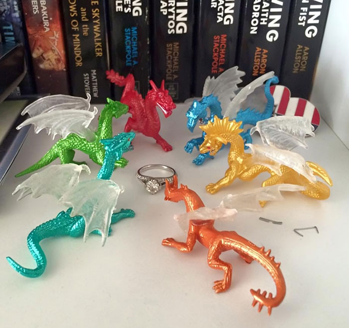Dragones de colores rodeando un anillo, destacando la creatividad de novios divertidos.