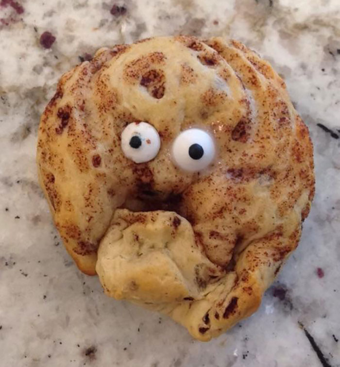 Galleta deformada con ojos comestibles, mostrando expresión divertida y extraña, en una superficie manchada, personas con día peor.