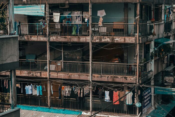 Edificio deteriorado con ropa colgada en balcones y cables eléctricos, reflejando momentos para irse rápidamente.
