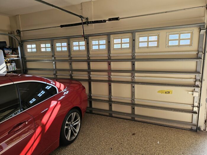 Coche rojo estacionado en garaje con puerta automática, ejemplo de objetos aparentemente inofensivos con peligro oculto.