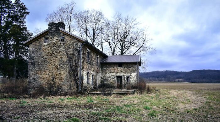 Casa abandonada en campo abierto con árboles y cielo nublado, momento para saber que había que irse ya mismo