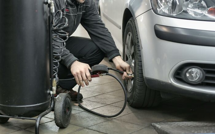 Persona usando equipo para inflar llantas de auto, mostrando actividades aparentemente inofensivas pero con mucho peligro.