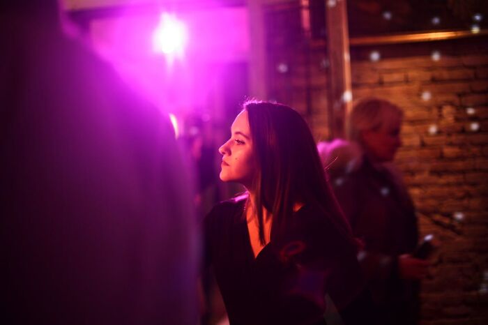 Mujer en ambiente nocturno iluminado con luces moradas, reflejando el momento de saber que tenía que irse ya mismo.