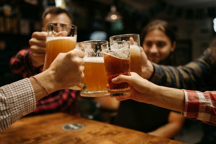 Personas brindando con vasos de cerveza, ejemplificando actividades aparentemente inofensivas pero con mucho peligro.