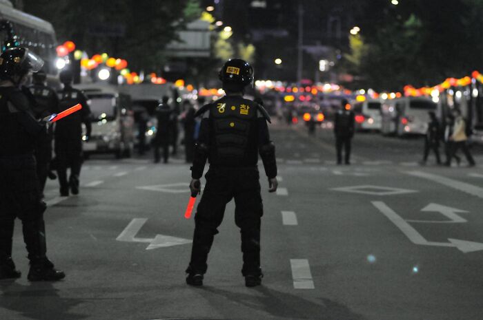 Agentes de seguridad con luces rojas en la mano controlan una calle en la noche, momento para irse ya mismo.