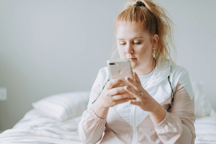 Mujer joven con expresión pensativa usando un teléfono móvil, momento de darse cuenta que no se casará con su pareja.