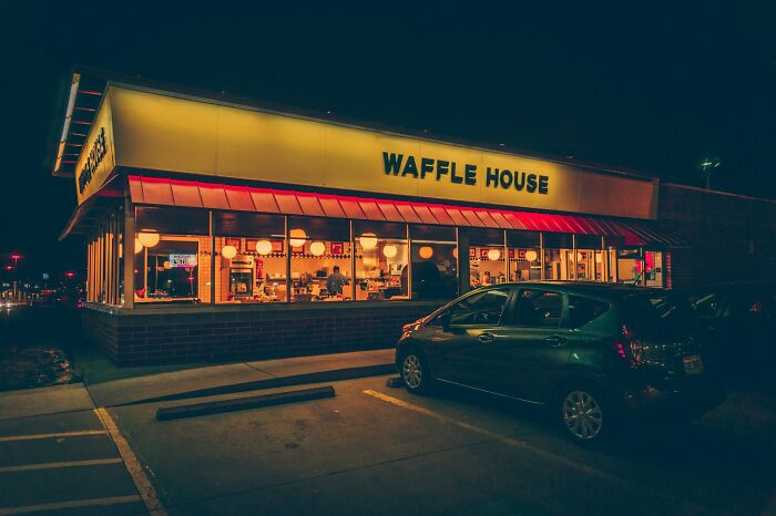 Restaurante Waffle House iluminado de noche con personas dentro, capturando momentos para salir ya mismo.