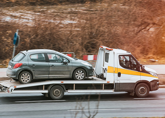 Automóvil gris siendo remolcado por una grúa en carretera, posible consecuencia de ignorar un 