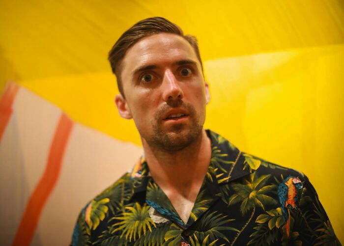 Hombre con expresión sorprendida usando camisa tropical, momento en que supo que tenía que irse ya mismo.