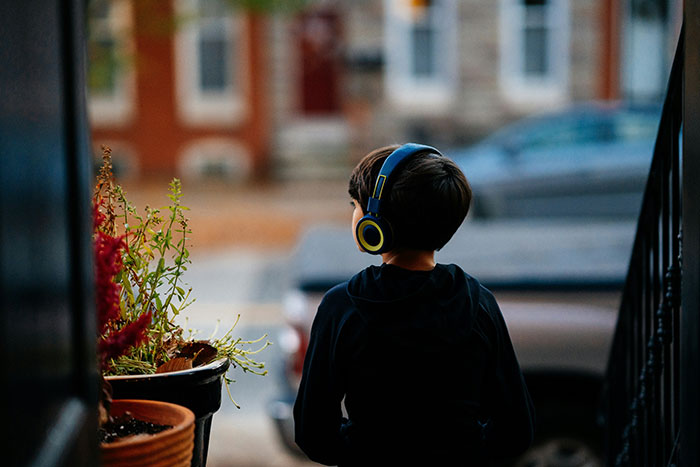 Niño con auriculares sentado de espaldas en un porche, ilustrando personas que previnieron una tragedia por si acaso.
