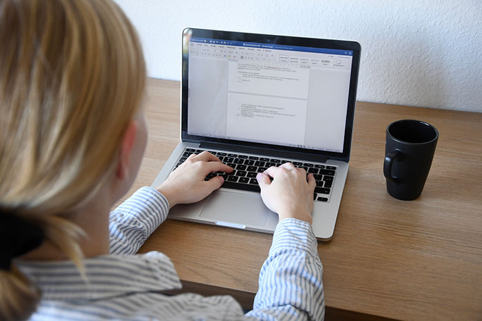 Persona escribiendo en laptop con café al lado, ilustrando personas que previnieron una tragedia por si acaso.