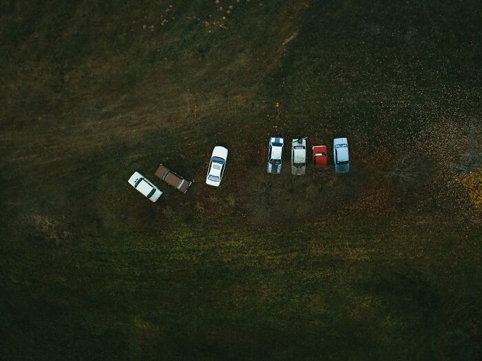 Vista aérea de varios coches estacionados en campo abierto, reflejando momentos para saber que tenían que irse ya mismo.