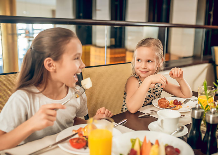 Dos niñas desayunando juntas, compartiendo una experiencia alegre en un restaurante.