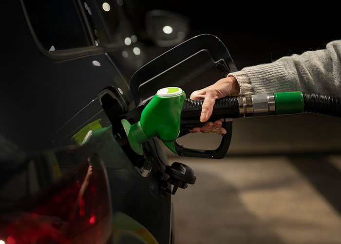 Persona cargando gasolina en un coche oscuro, representando experiencias salvajes que exigen irse rápidamente.